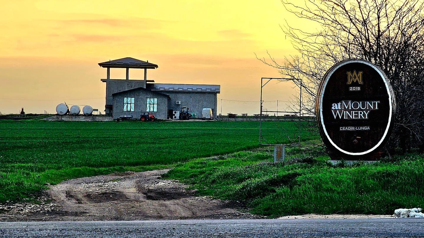 Sunset view of Mâmount Winery with vineyard entrance sign and rural landscape
