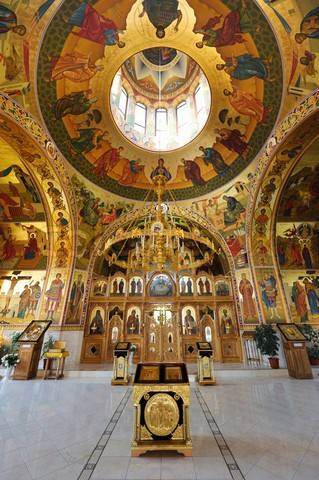 Orthodox monastery interior with ornate dome, iconostasis, and Byzantine frescoes