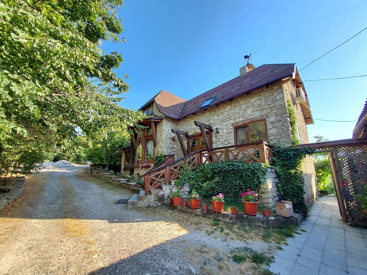 Stone cottage facade with wooden terrace, garden entrance, and ivy-covered walls