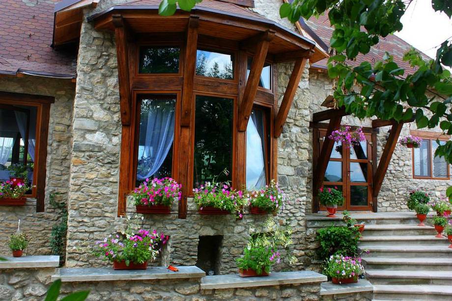 Stone facade with wooden accents, flowering planters, and welcoming entrance steps