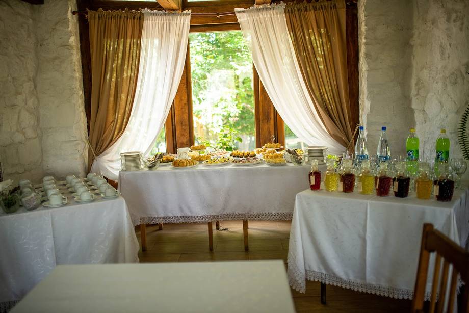 Elegant room with draped windows, fresh flowers and bottled beverages on table