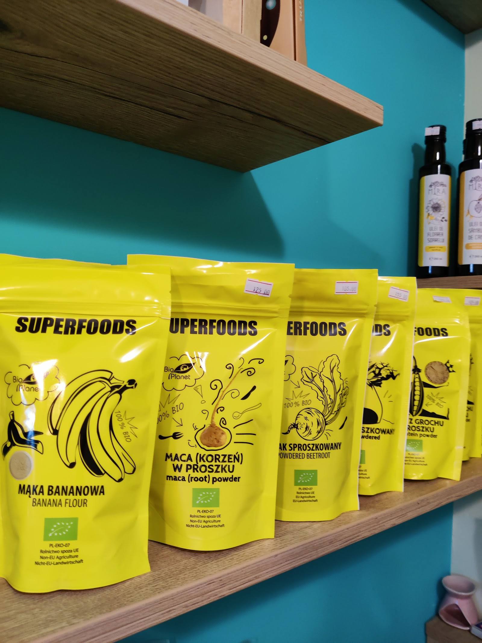 Superfoods product line displayed on turquoise shelving with wooden shelf and bottles