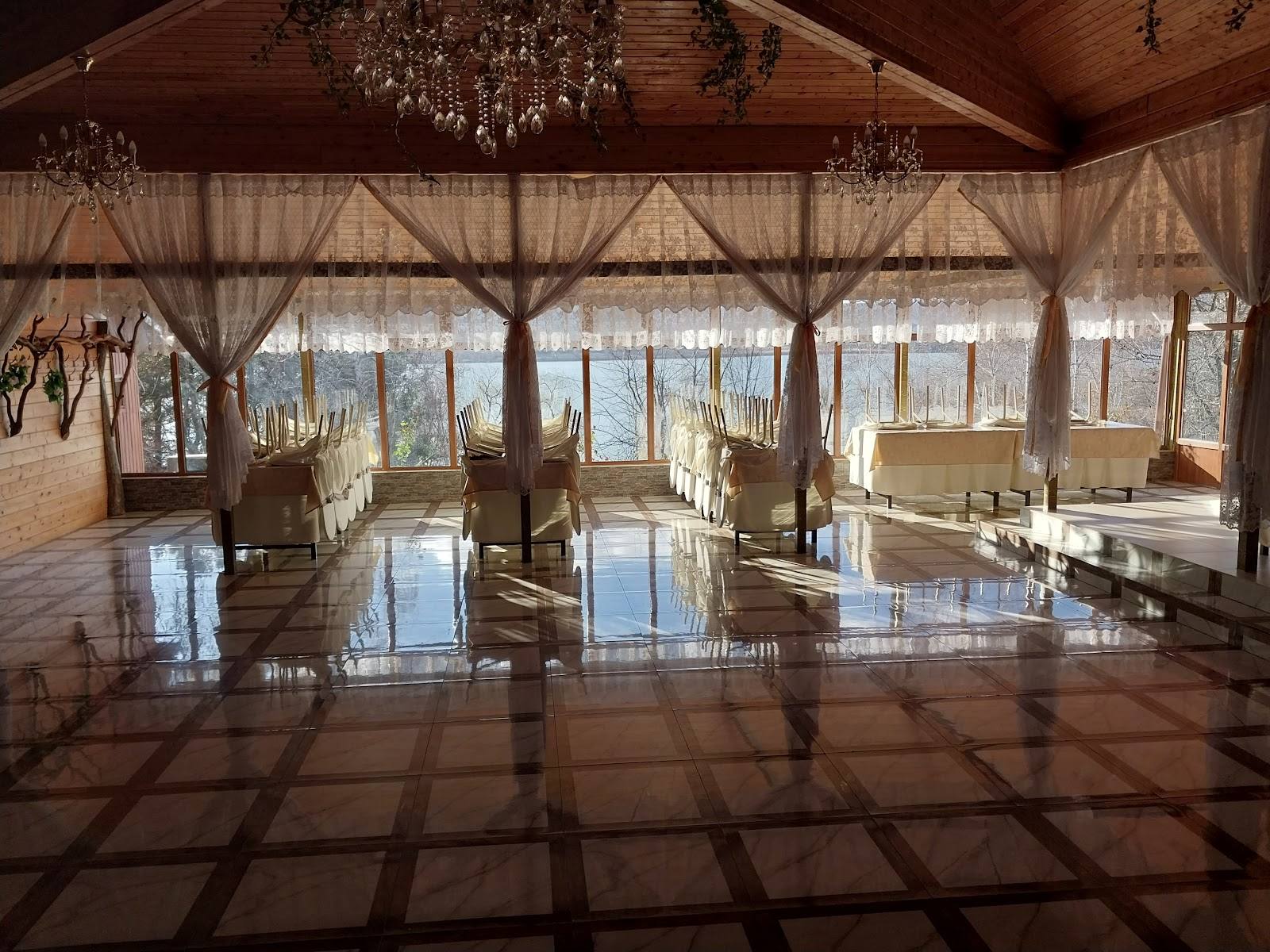 Elegant event hall with polished wood floors, vaulted ceiling, and panoramic windows overlooking gardens