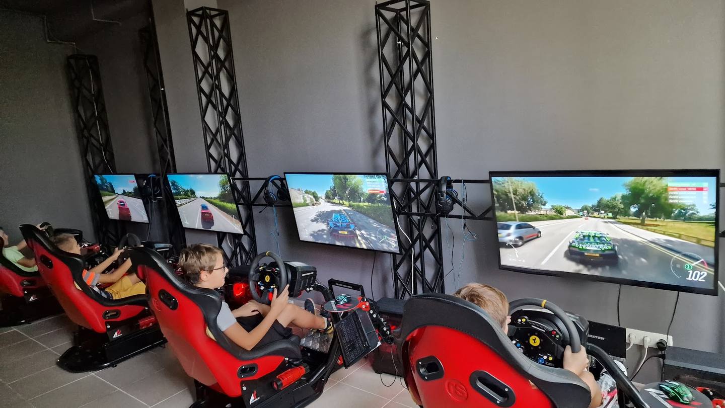 Racing simulator cockpits with multiple screens and professional racing setup