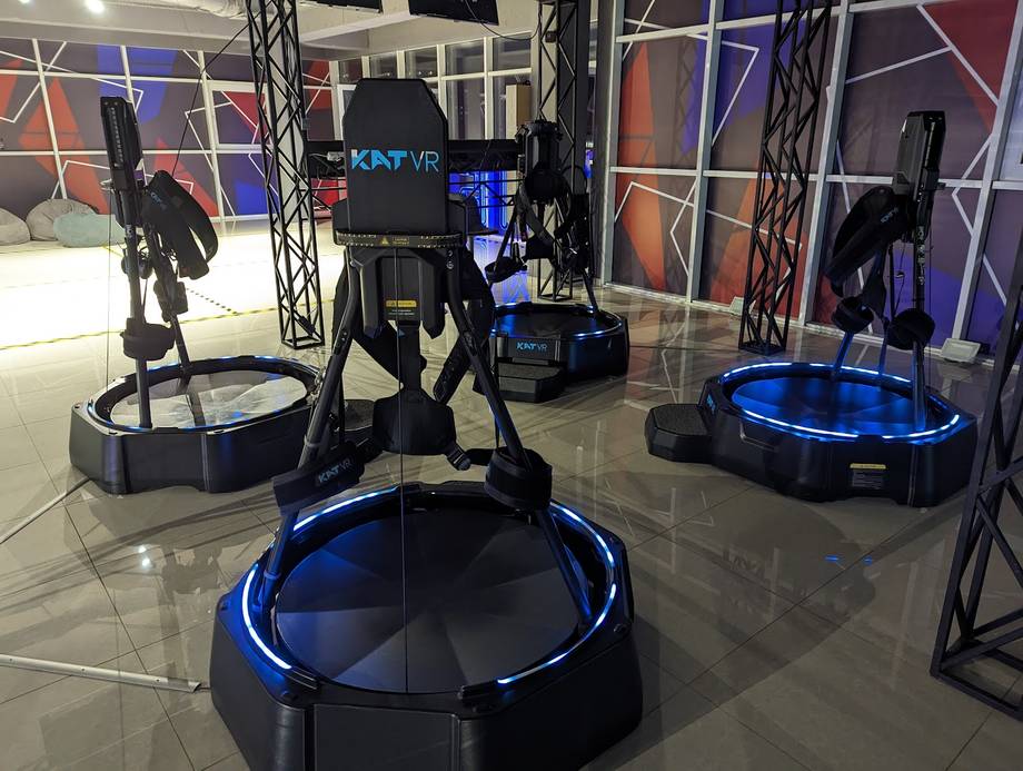 VR gaming arena with blue-lit motion platforms and interactive stations