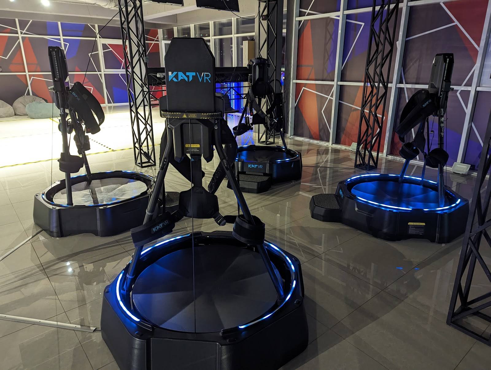 VR gaming arena with blue-lit motion platforms and interactive stations