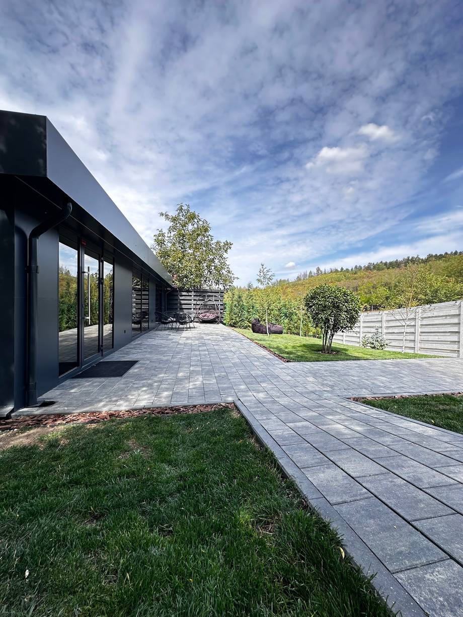 Modern black building with paved terrace and landscaped grounds