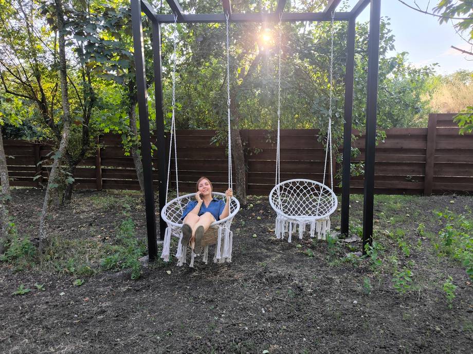 Person on hanging chair swing in backyard garden setting