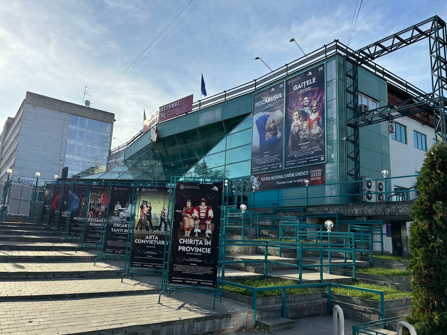 Modern cultural venue exterior with distinctive tilted architecture and event banners