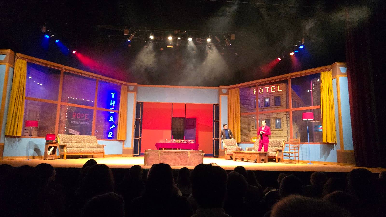 Theater stage with colorful set design and audience silhouettes in foreground