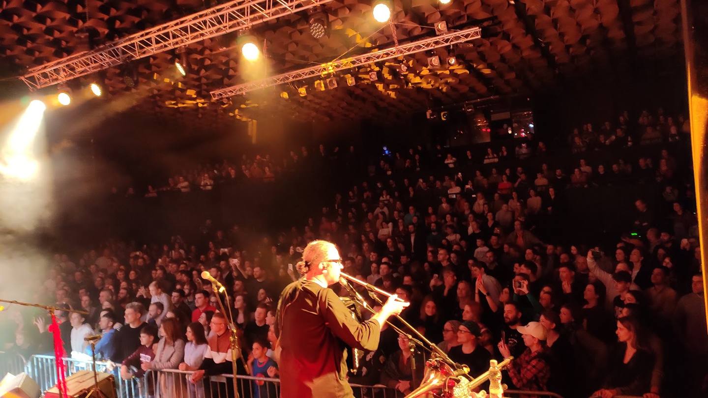 Live band performance on stage with crowded audience and stage lighting