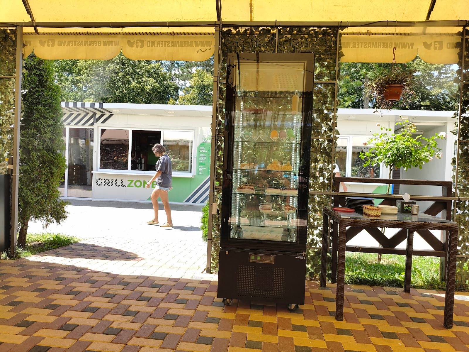 Grill-focused restaurant entrance with ivy-draped storefront and outdoor seating area
