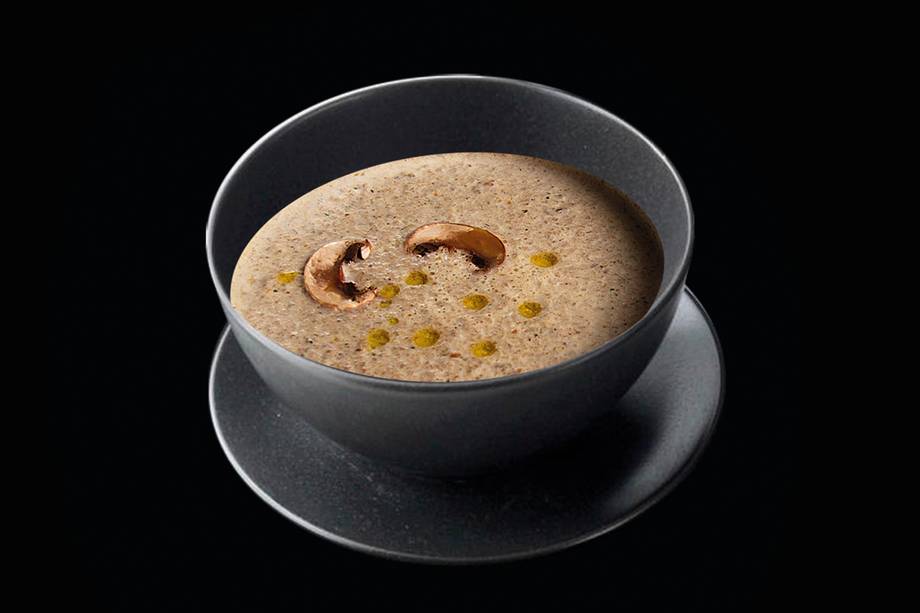 Creamy mushroom or truffle soup in dark ceramic bowl with garnish