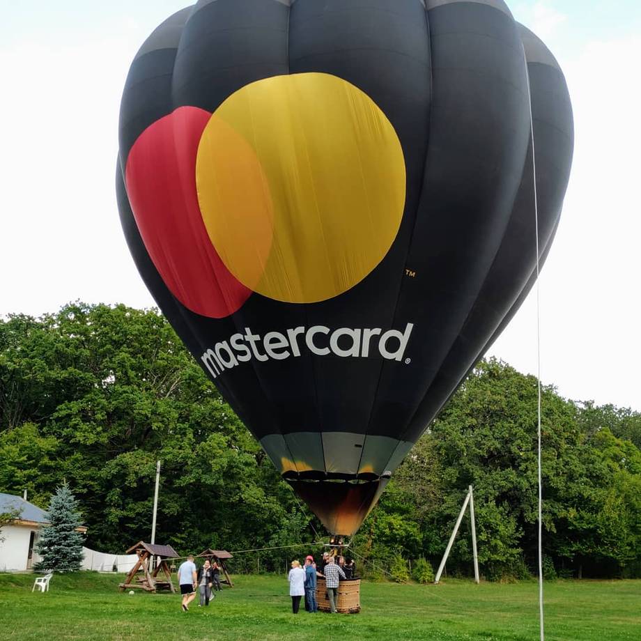 Hot air balloon with Mastercard branding during inflation on grass field