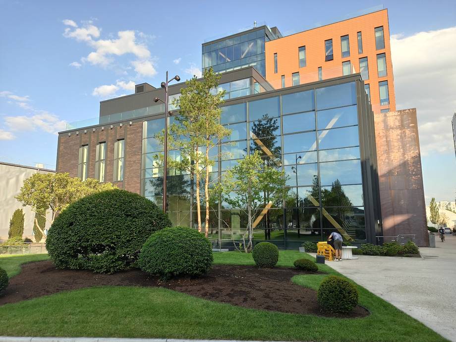 Modern event venue with distinctive orange facade and glass atrium, manicured grounds and landscaping
