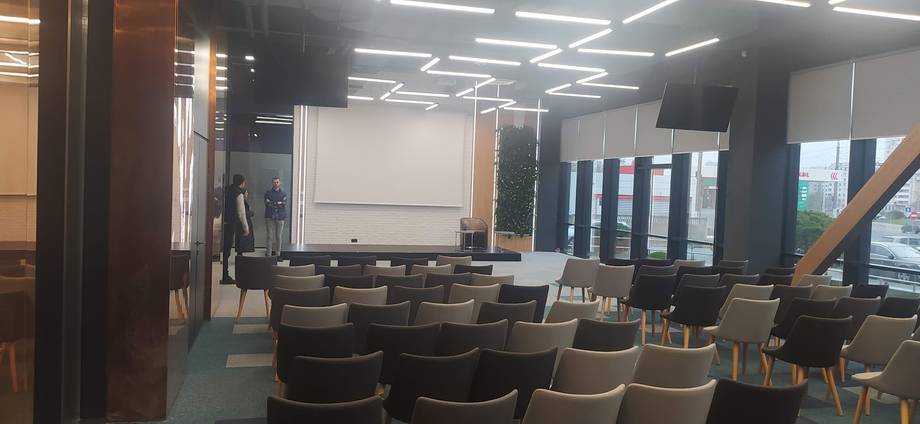 Modern event or conference space with rows of tiered seating and projection screen