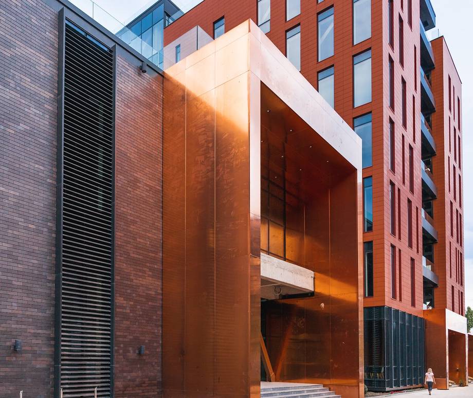 Modern brick facade with illuminated bronze-clad storefront entrance at twilight