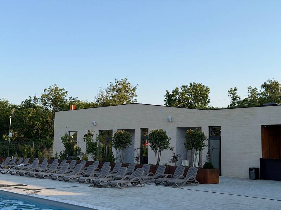 Modern white poolside pavilion with sunbed lounge area and landscaped grounds
