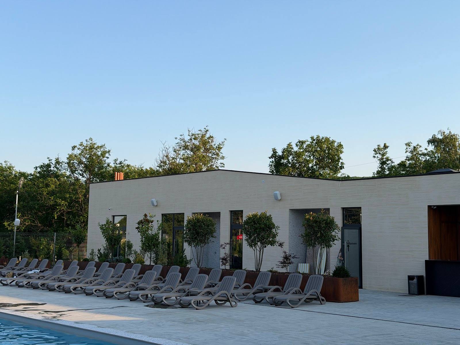 Modern white poolside pavilion with sunbed lounge area and landscaped grounds