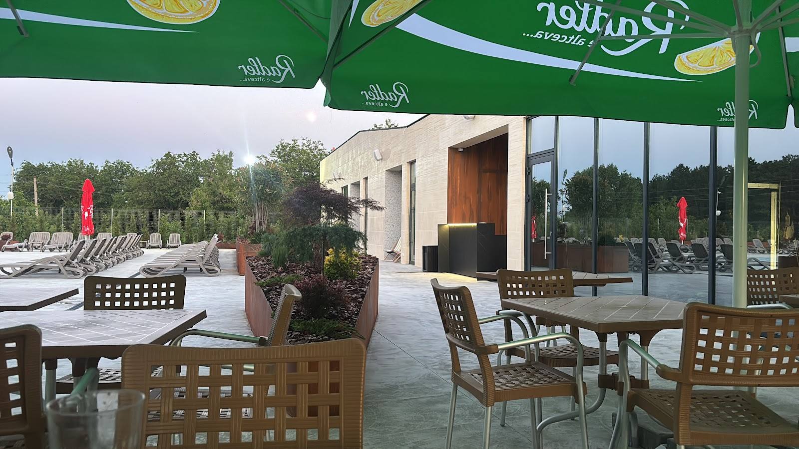 Outdoor terrace with green umbrellas, wooden furniture, and modern glass-enclosed dining space