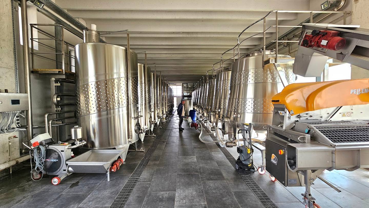Modern winery production hall with stainless steel fermentation tanks and equipment