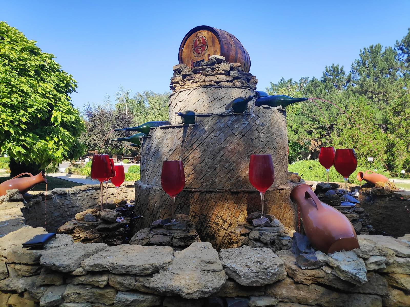 Oversized wine barrel sculpture with large red wine glasses in outdoor setting