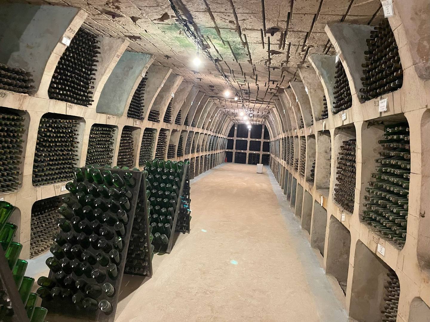 Wine cellar with bottles stored in alcoves along arched stone corridor