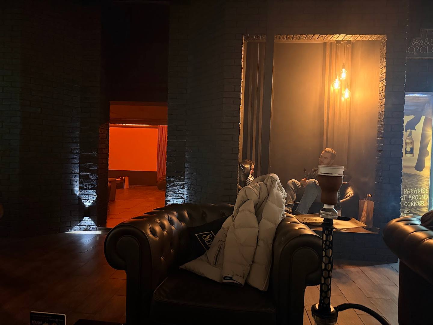 Lounge interior with leather seating and ambient warm lighting, leading to dining area