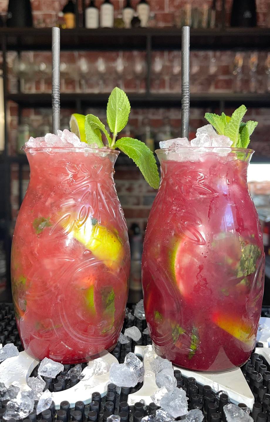 Signature cocktails with fresh mint and citrus garnish served over crushed ice at the bar