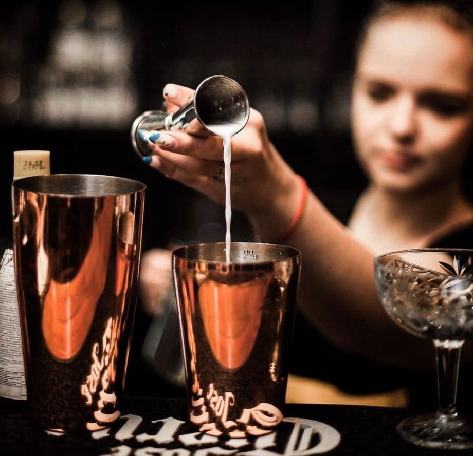 Bartender pouring cocktail with professional technique at craft bar