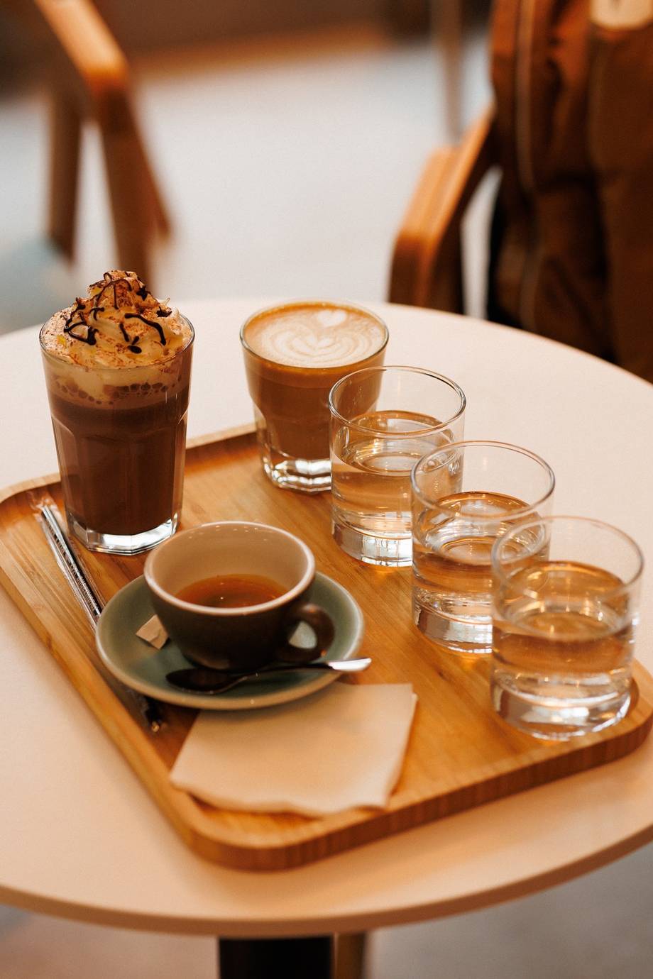 Coffee tasting flight with espresso, water glasses, and specialty beverages on wooden tasting board