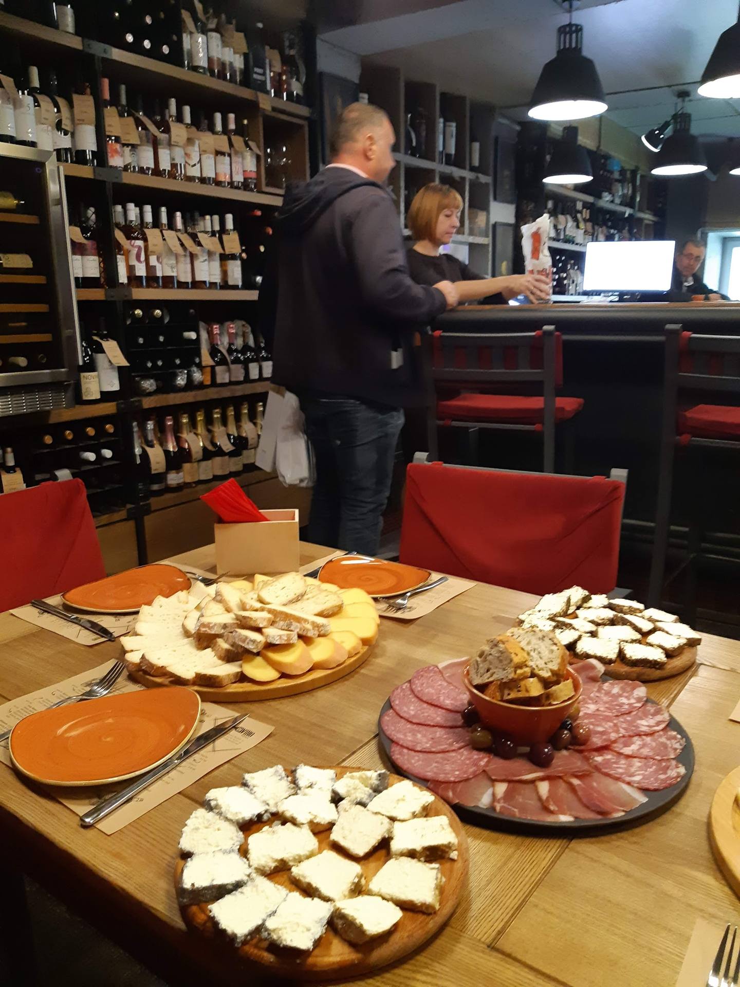 Charcuterie and cheese platters at wine bar counter with staff and bottle display