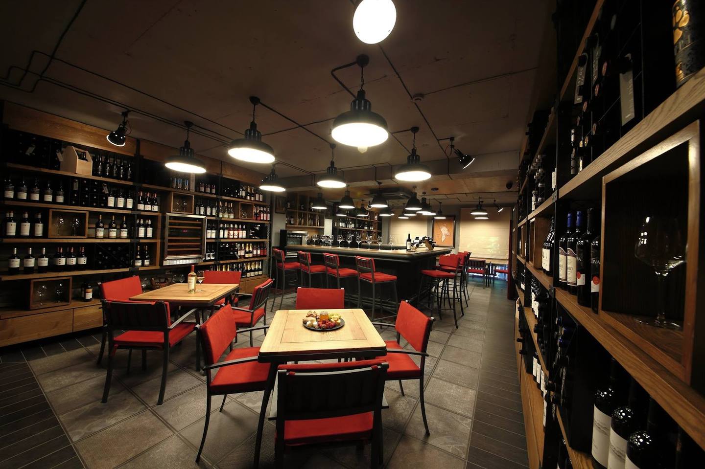 Wine bar interior with floor-to-ceiling bottle displays, red seating, and warm ambient lighting