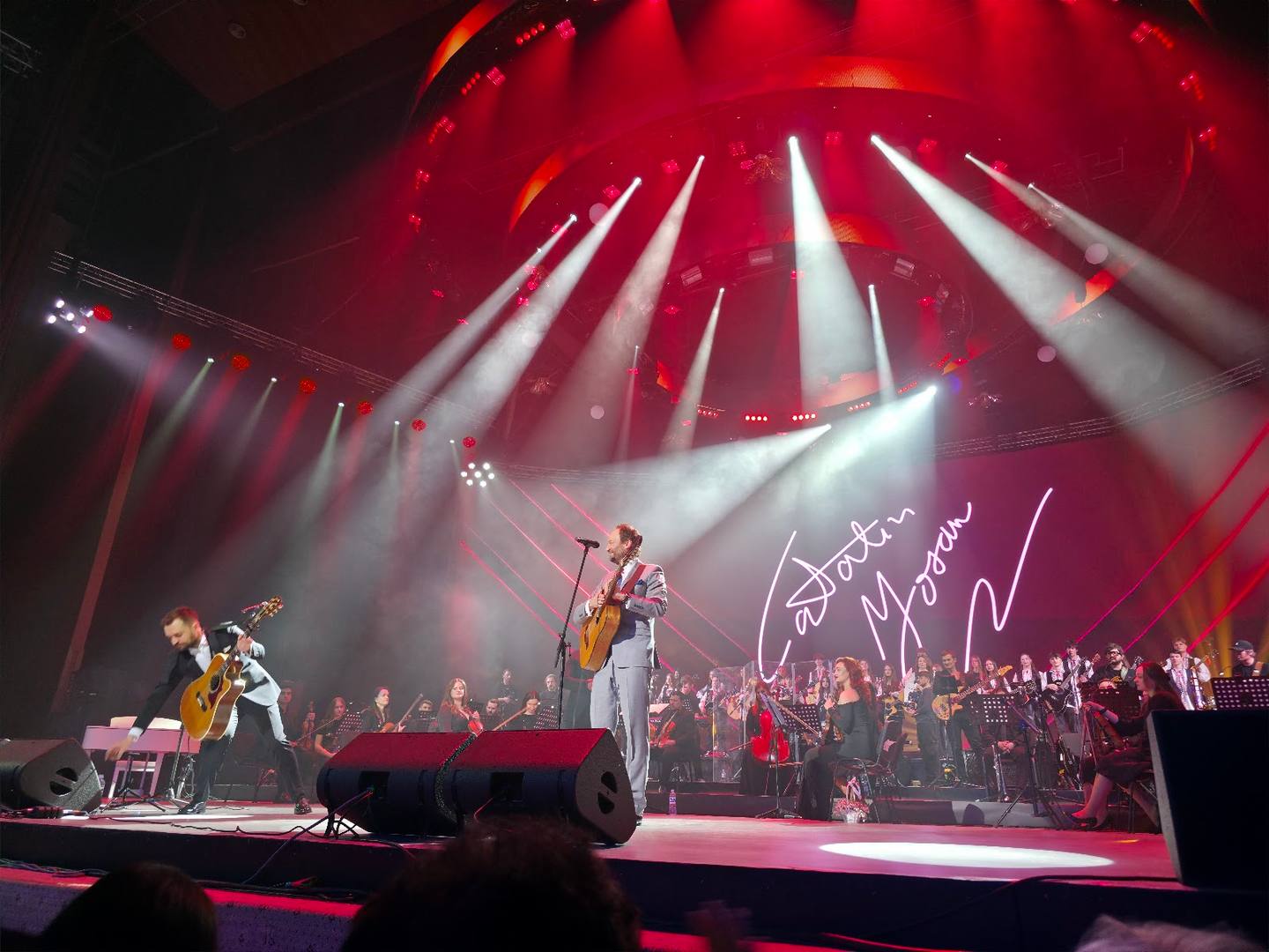 Live concert stage with dramatic red lighting and full band performance