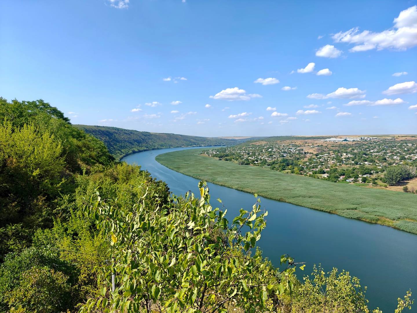 Panoramic river valley landscape with verdant rolling hills and clear sky