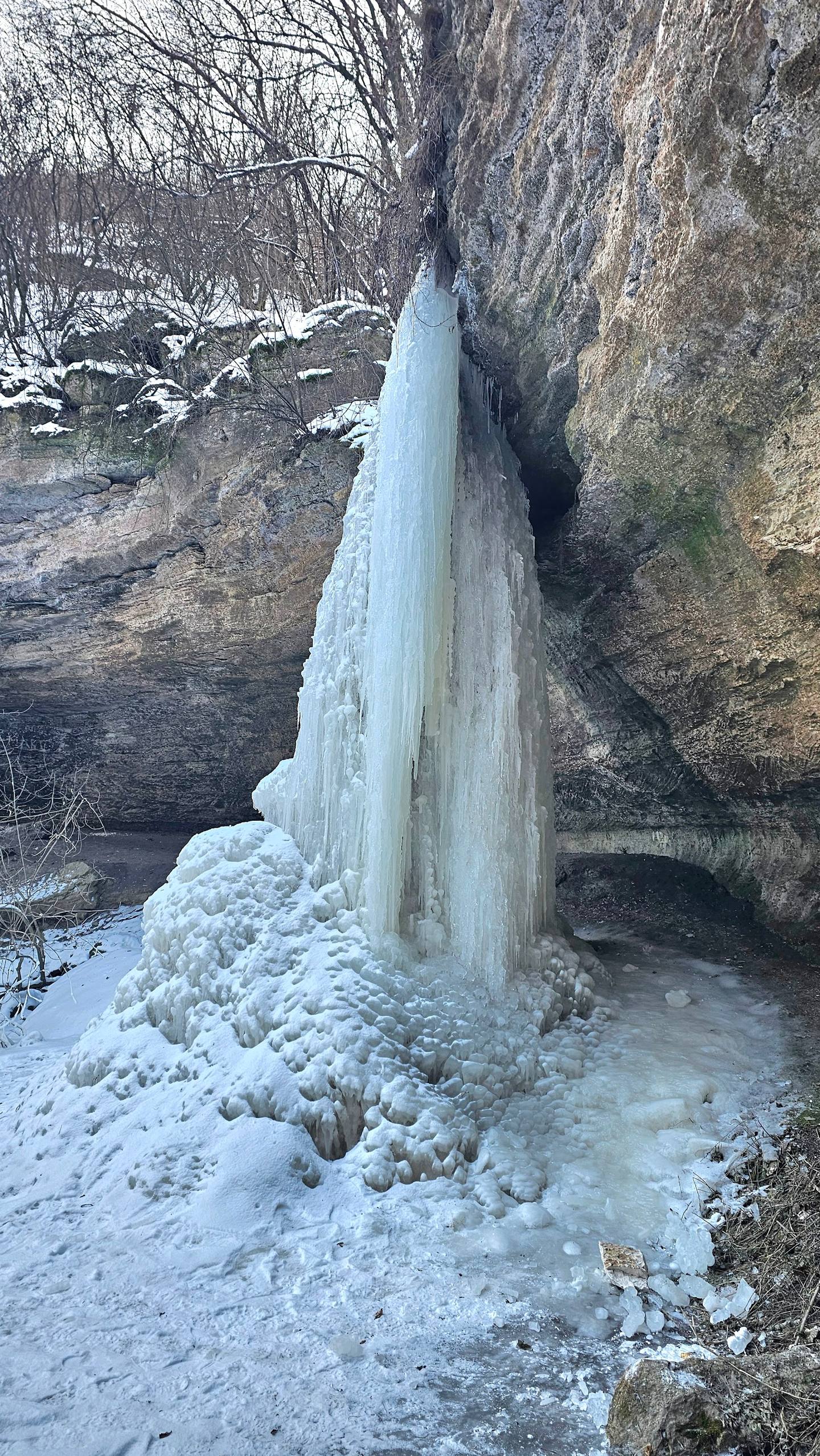 Frozen waterfall cascade between rocky cliffs in winter landscape