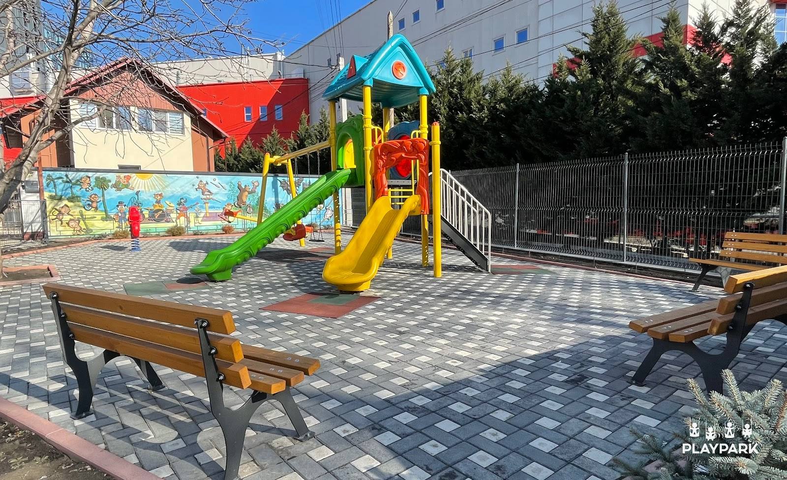 Bright playroom with colorful playground equipment, wooden seating, and patterned flooring