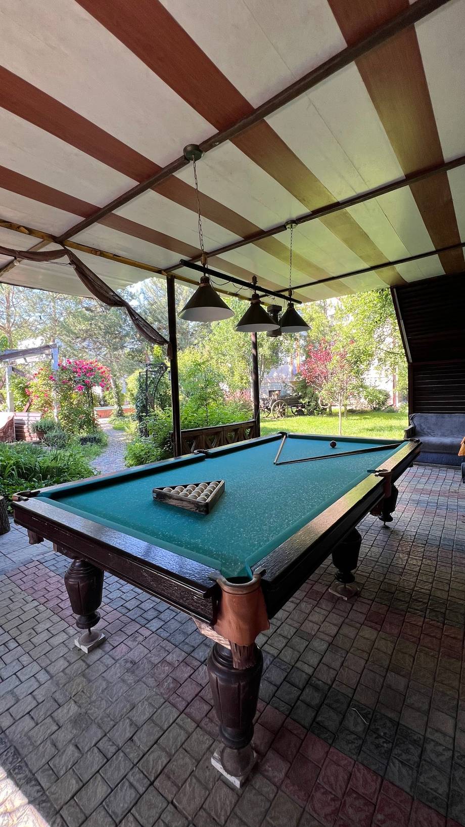 Billiards table under pergola with garden views in covered outdoor space