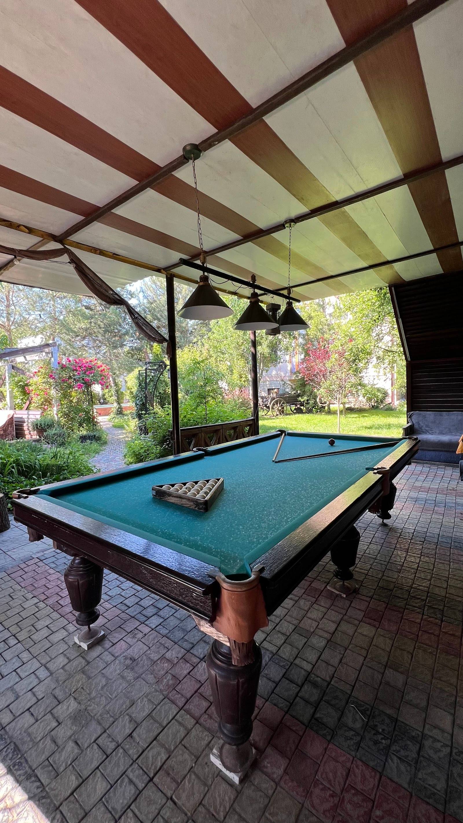 Billiards table under pergola with garden views in covered outdoor space