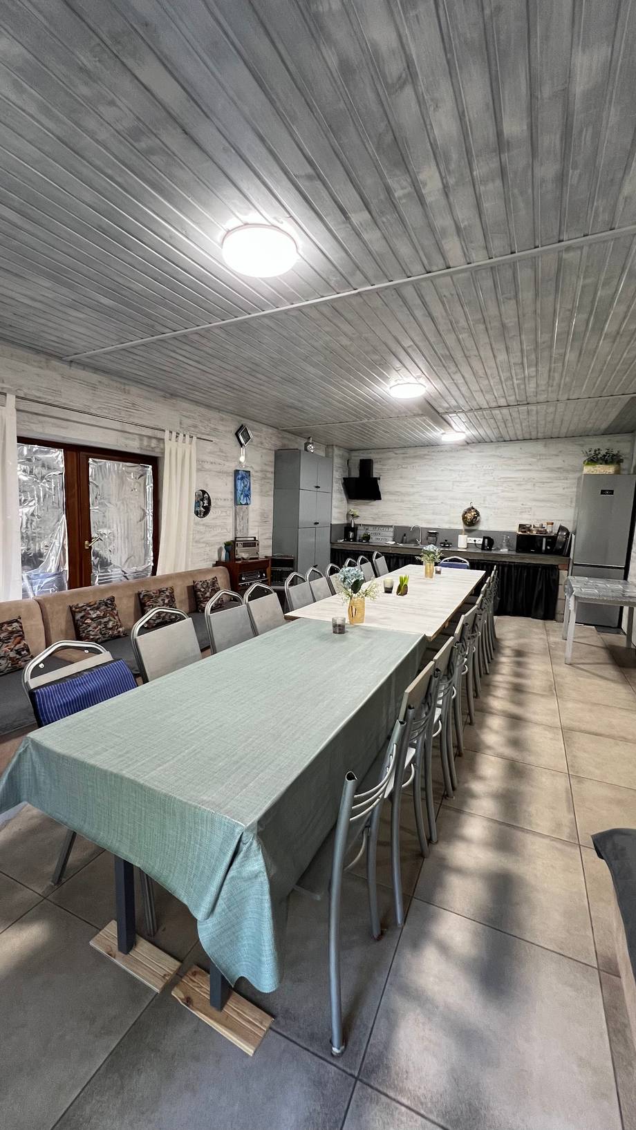 Open-plan dining and kitchen space with striped metal ceiling and bright natural light