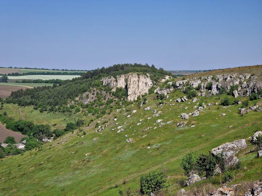 Rocky limestone hillside with green pasture and cultivated valley landscape in Moldova