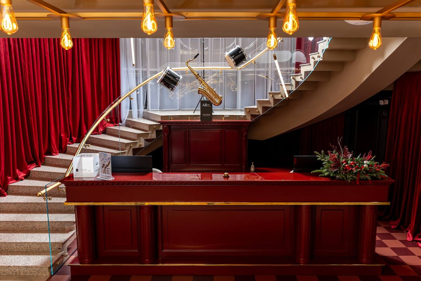 Luxury hotel lobby with grand staircase, reception desk, and brass pendant lighting