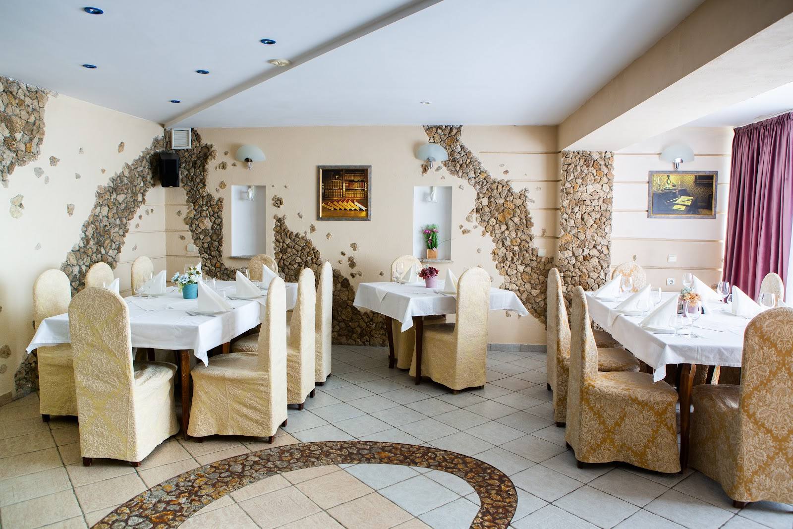 Restaurant dining room with beige upholstered chairs and white tablecloths