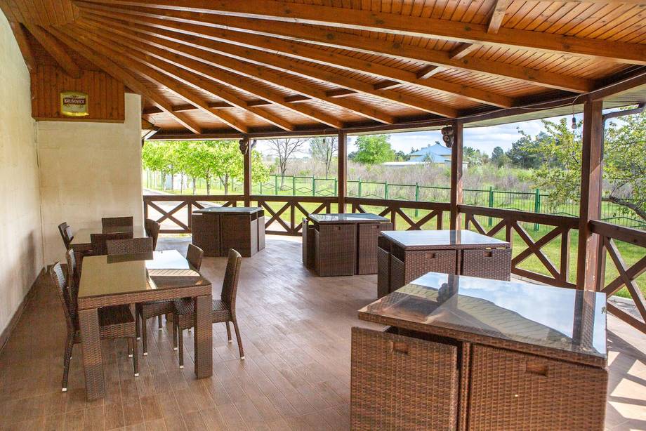 Covered terrace with wooden ceiling and countryside views, furnished with tables and seating