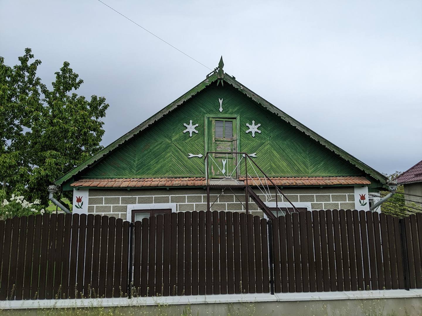 Traditional green wooden monastery building with decorative cross and geometric patterns on gable
