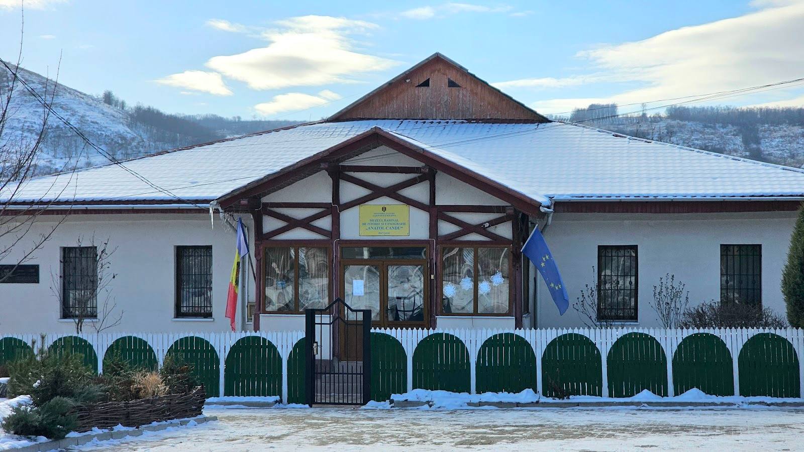 White-walled venue with timber-frame entrance pavilion, winter setting with mountain backdrop.