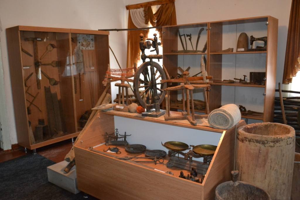Museum display of traditional wooden tools and crafts with spinning wheel and period artifacts