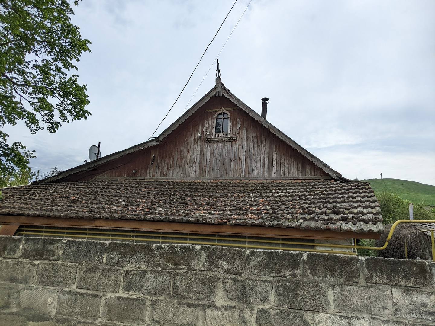 Traditional wooden chapel with shingled roof and stone foundation, Moldova countryside