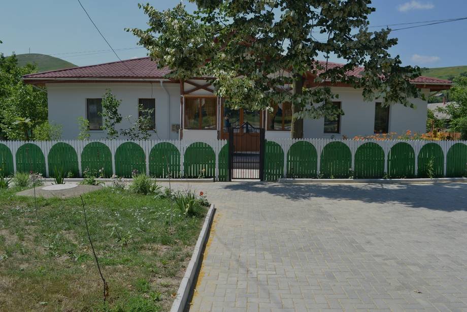 White facade with green fence and arched entrance, Moldova village venue
