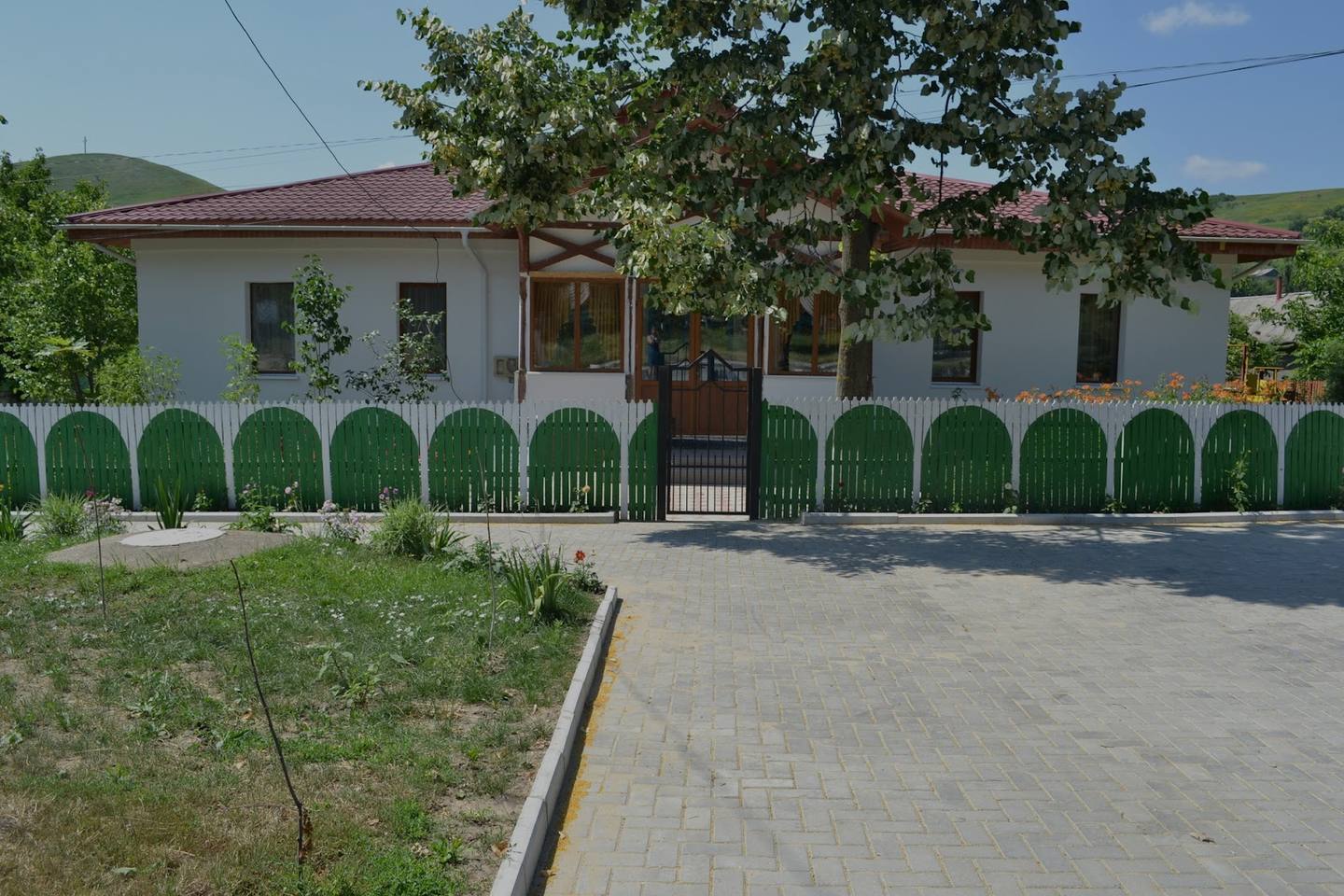 White facade with green fence and arched entrance, Moldova village venue